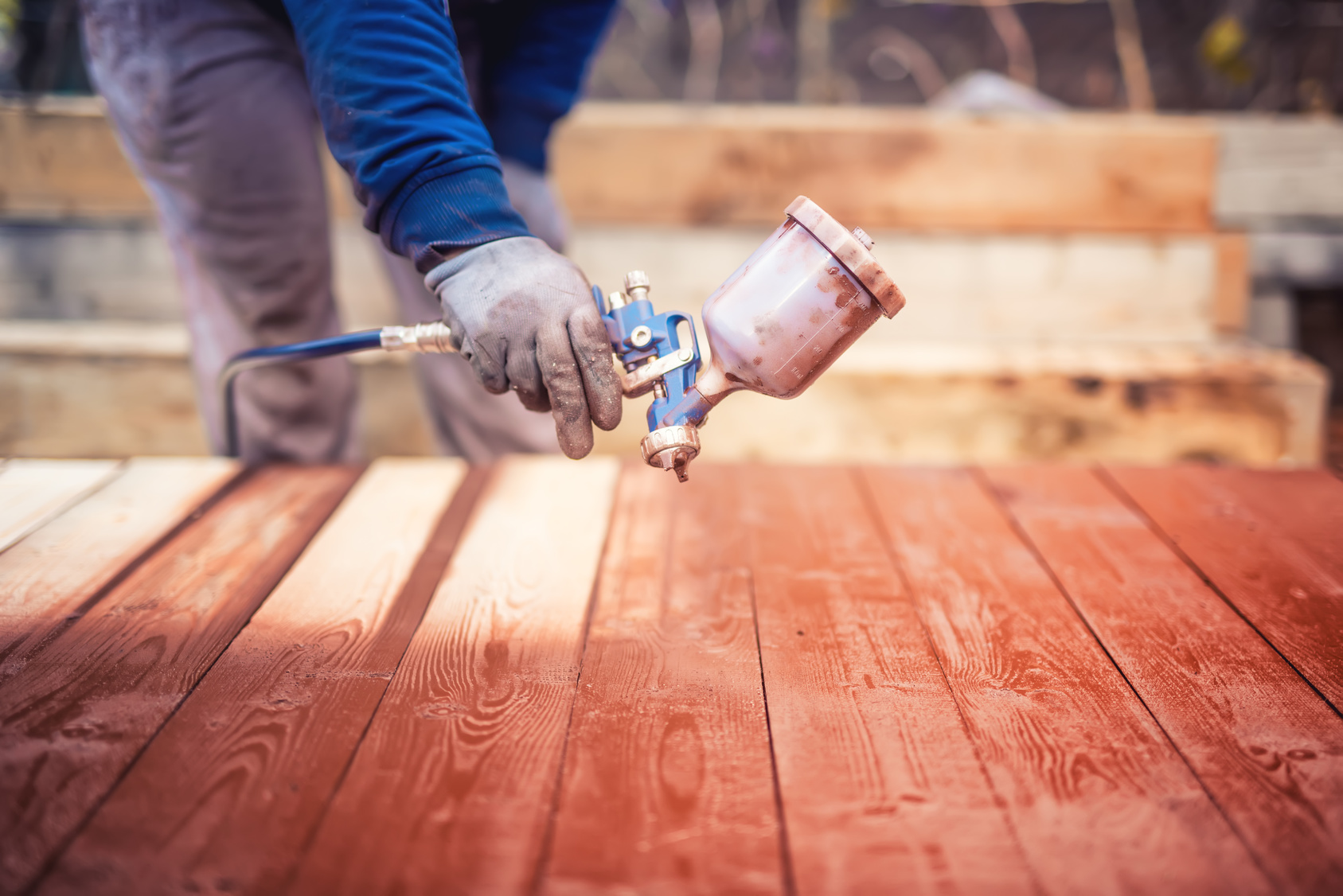 Industrial handyman, construction worker painting with spray gun on site